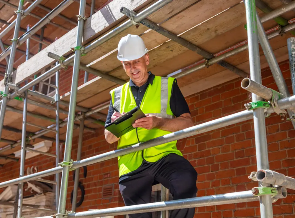 Construction worker standing on scaffolding on building site in the UK